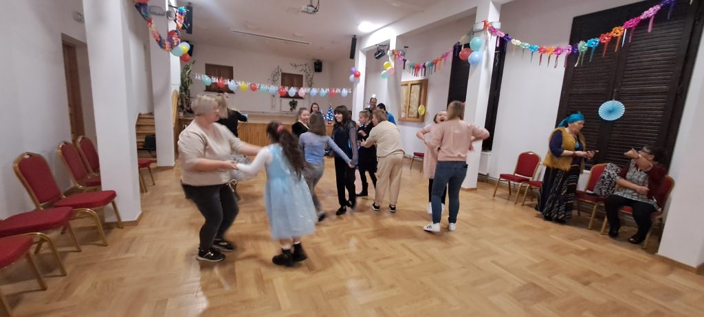 ozdobiona balonami i girlandami sala balowa a pośrodku tańczące dzieci