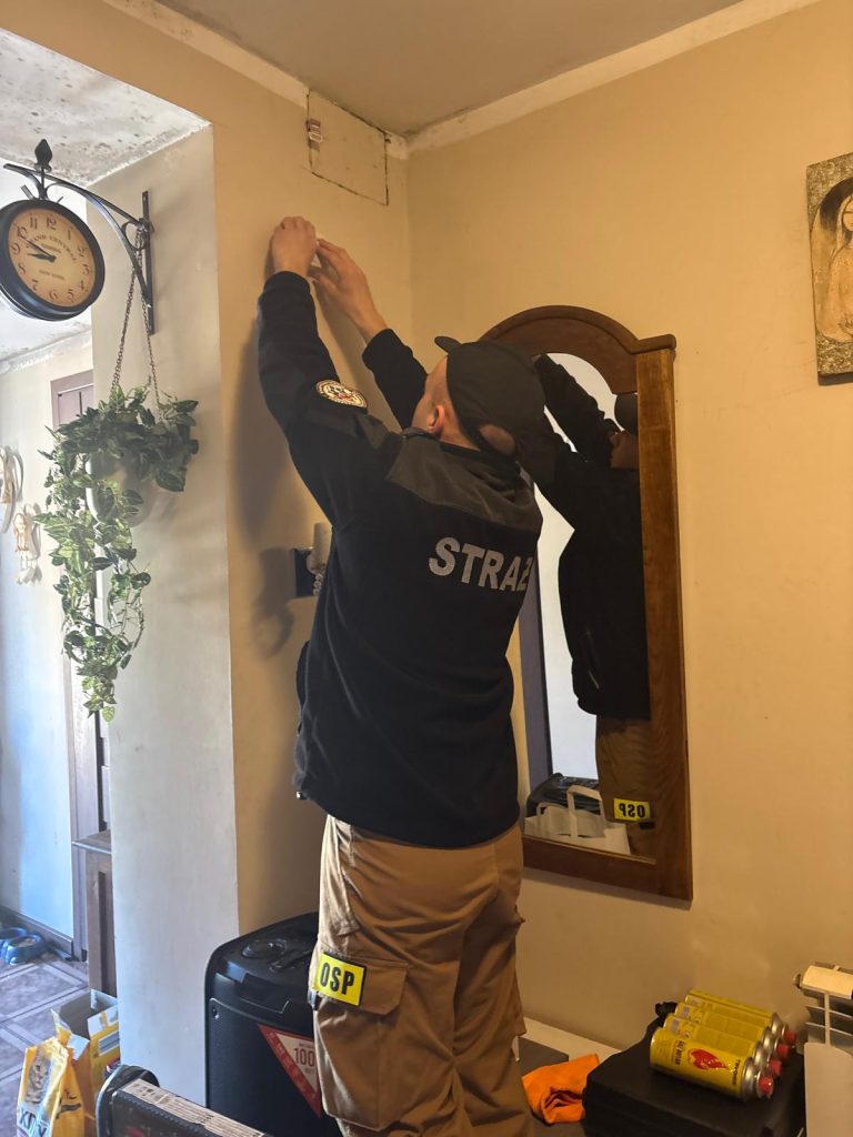 Strażak montujący czujkę dymu na ścianie pokoju